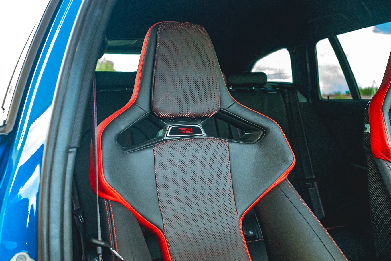 Nowoczesny, sportowy fotel samochodowy z czerwonymi przeszyciami i oznaczeniem sportowej wersji RS, umieszczony w przestronnym wnętrzu pojazdu.