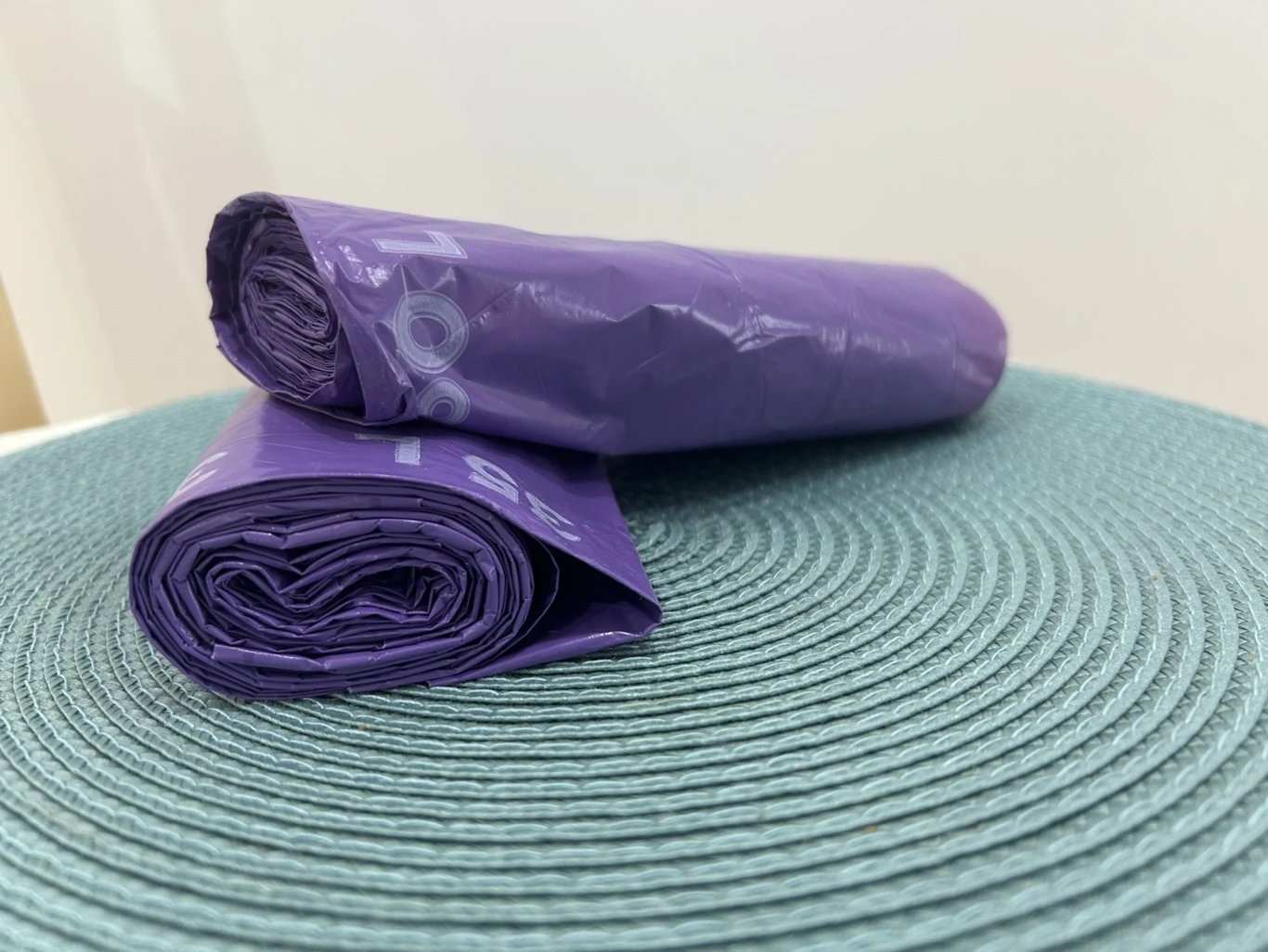 Od października pojawią się fioletowe worki na śmieci (zdj. ilustracyjne) Dwie fioletowe rolki worków na śmieci leżące na turkusowej, teksturowanej powierzchni maty, ustawione równolegle do siebie.