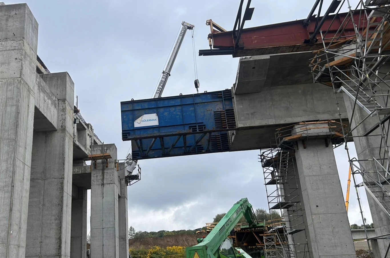 S7 Kraków. Wielkie przesuwanie estakady na Węźle Mistrzejowice. Trwa montaż dużego elementu stalowego na betonowej konstrukcji mostu przy użyciu dźwigu, wokół widoczne są rusztowania i sprzęt budowlany.