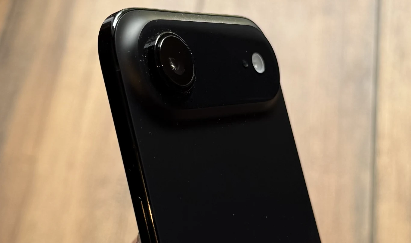 Czarny smartfon z metaliczną ramką, widoczną dużą pojedynczą soczewką aparatu oraz lampą błyskową umieszczoną na tylnej części obudowy.