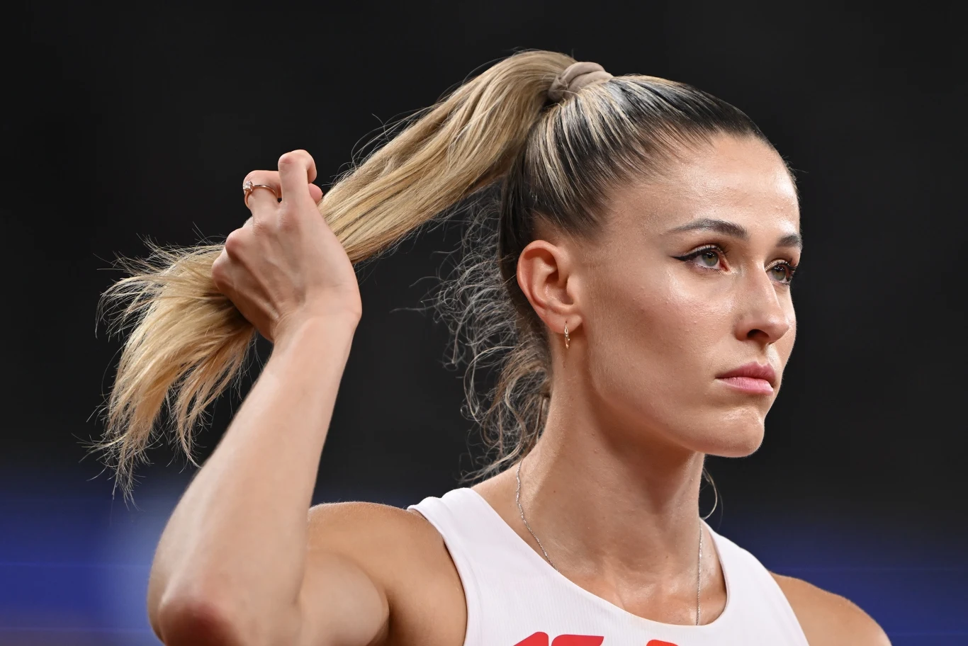 Natalia Bukowiecka Sportowczyni o długich, blond włosach spiętych w kucyk, w sportowym stroju, poprawia fryzurę w trakcie zawodów, skupiona i poważna wyraz twarzy.
