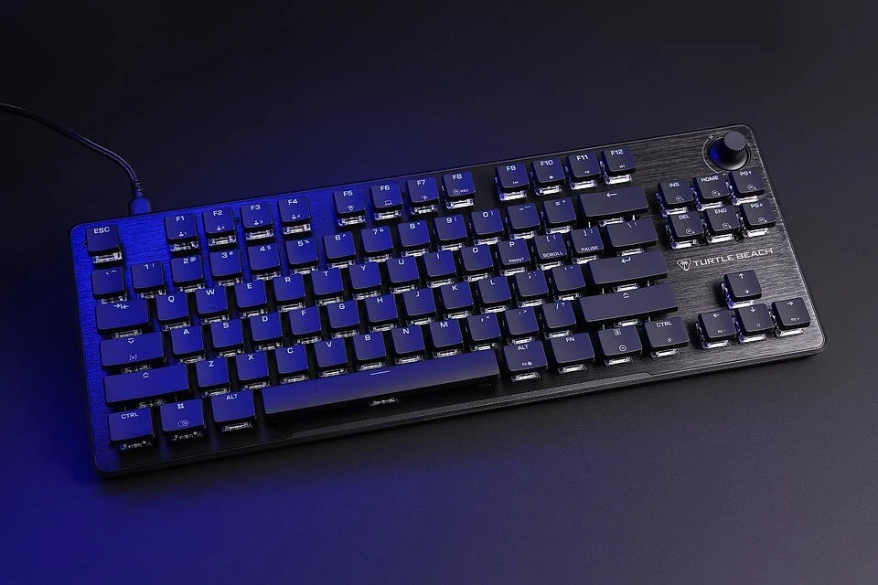 Czarna klawiatura mechaniczna marki Turtle Beach na ciemnym tle, podświetlona delikatnym niebieskim światłem, widoczne przyciski funkcyjne oraz pokrętło w prawym górnym rogu.