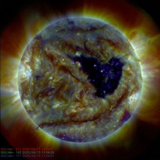 Powierzchnia Słońca z widocznymi koronami i ciemną plamą w centrum, dynamiczne wybuchy plazmy na tle kolorowych promieni słonecznych.