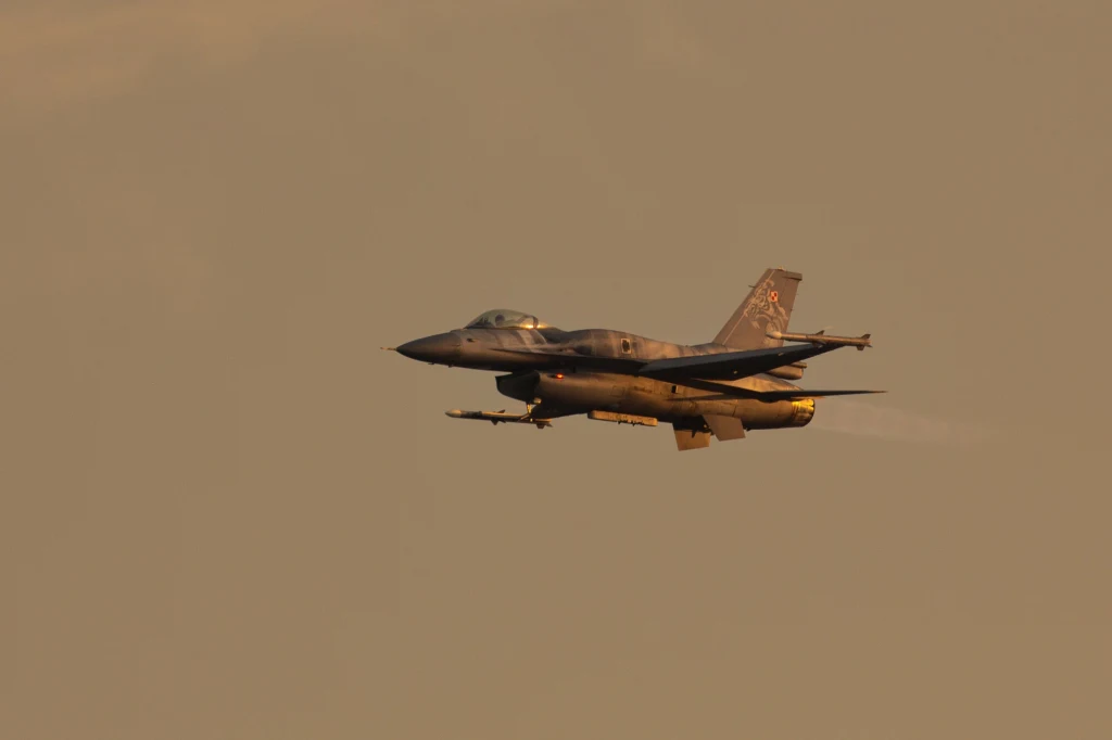 Rosyjski atak na Ukrainę. Polskie wojsko poderwało myśliwce, zdj. ilustracyjne Samolot myśliwski lecący na tle zachmurzonego nieba, widoczne uzbrojenie pod skrzydłami oraz oznaczenia wojskowe na kadłubie.