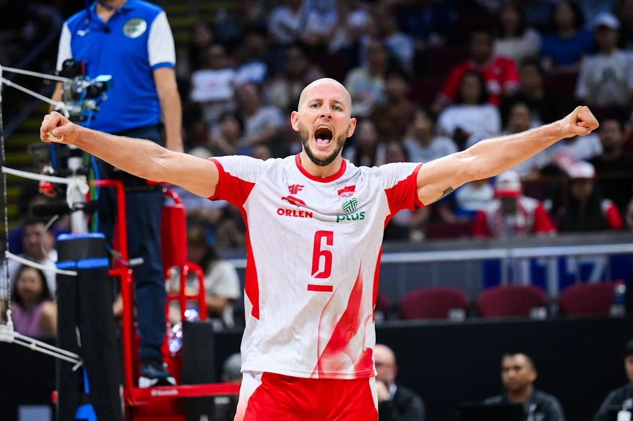 Siatkówka, Polska - Kanada. Bartosz Kurek po raz kolejny pokazał się z dobrej strony Siatkarz w białoczerwonym stroju z numerem 6, stojący na boisku z uniesionymi ramionami, wyrażający radość lub triumf, w tle rozmyta publiczność na trybunach.