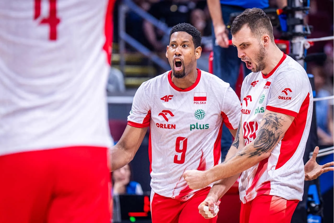 Wilfredo Leon i Norbert Huber Dwóch polskich siatkarzy w biało-czerwonych strojach okazuje emocje i gesty radości po udanym zagraniu podczas meczu siatkówki, w tle widoczne trybuny z kibicami.