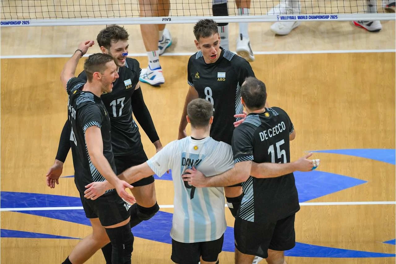 Grupa siatkarzy świętujących zdobyte punkty na boisku, zawodnicy ubrani w sportowe stroje, w tle siatka do siatkówki i parkiet sportowej hali.