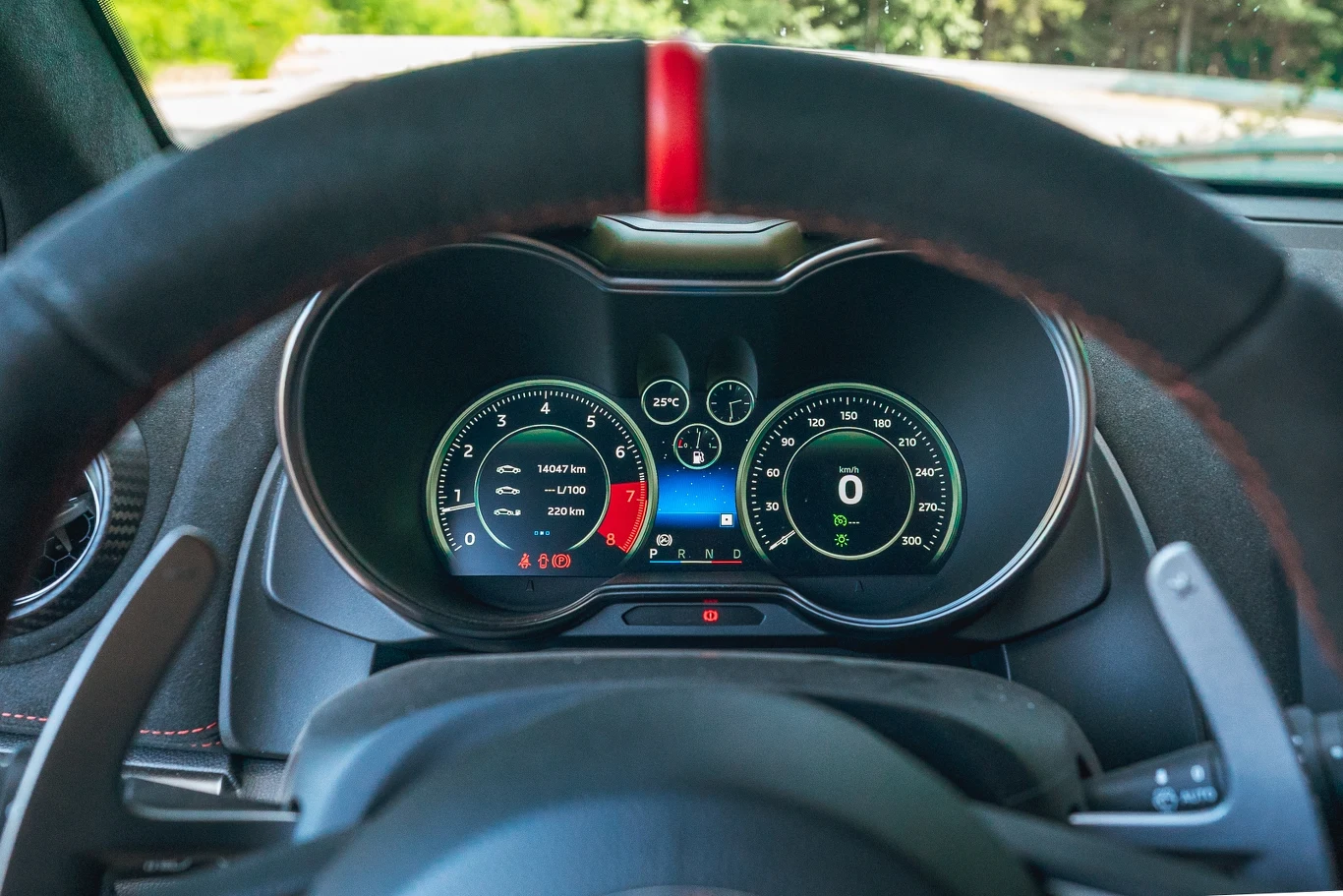 Alpine A110 R Cyfrowy zestaw wskaźników samochodu sportowego z widocznym kierownicą, wyświetlaczami prędkości, obrotów silnika, temperatury oraz poziomu paliwa, tło rozmyte i nieodciągające uwagi od panelu kontrolnego.