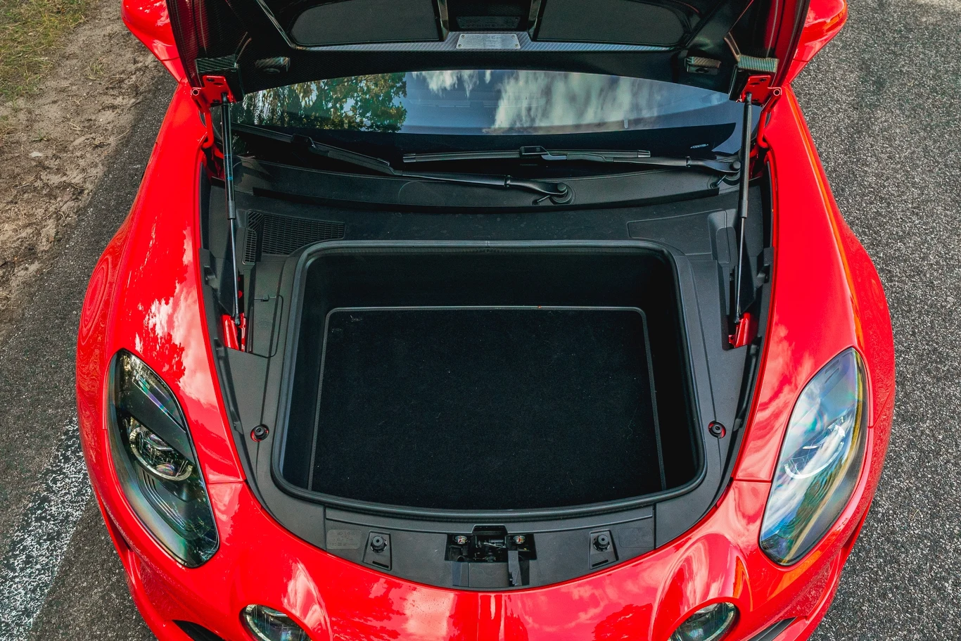 Alpine A110 R Przód czerwonego samochodu sportowego z otwartą maską, pod którą znajduje się pusty bagażnik umieszczony z przodu pojazdu.