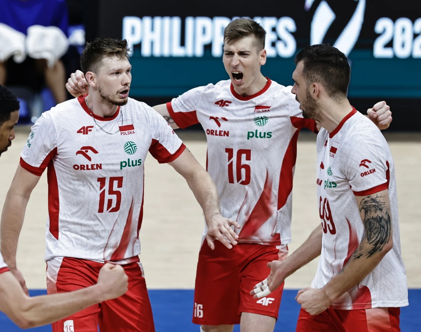 Trzech siatkarzy polskiej reprezentacji w biało-czerwonych strojach świętuje zdobyty punkt na parkiecie siatkarskim, okazując silne emocje i jedność drużynową.