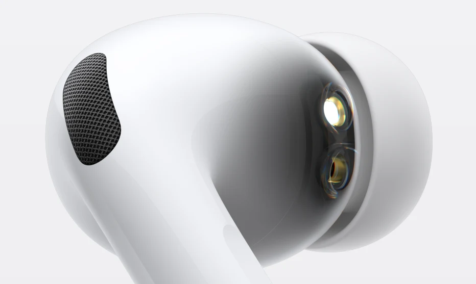 Detaliczny widok białej dousznej słuchawki bezprzewodowej z widoczną siatką na mikrofon oraz przezroczystą nakładką silikonową, uchwycony w dużym zbliżeniu na jasnym tle.