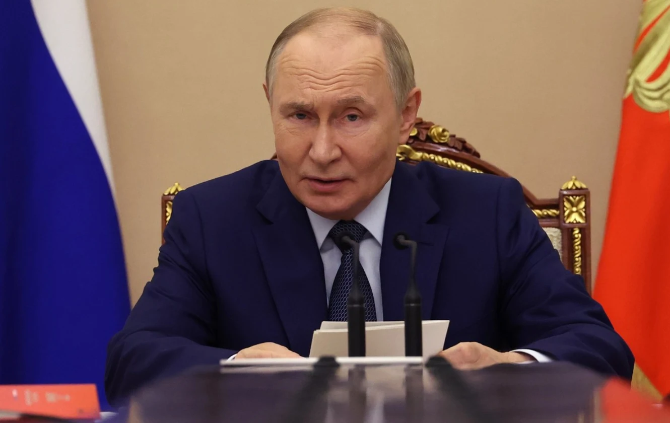 Władimir Putin powiedział o przyszłości traktatu New START Mężczyzna w garniturze siedzi przy stole, przed nim mikrofony i dokumenty, w tle widoczne są flagi.