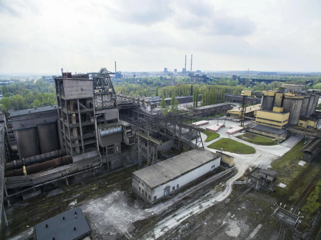 Kombinat w Nowej Hucie Kompleks przemysłowy z rozbudowanymi halami produkcyjnymi i magazynowymi, liczne instalacje techniczne, kominy fabryczne oraz przyległe tory kolejowe, otoczenie stanowią tereny zielone i przemysłowe.