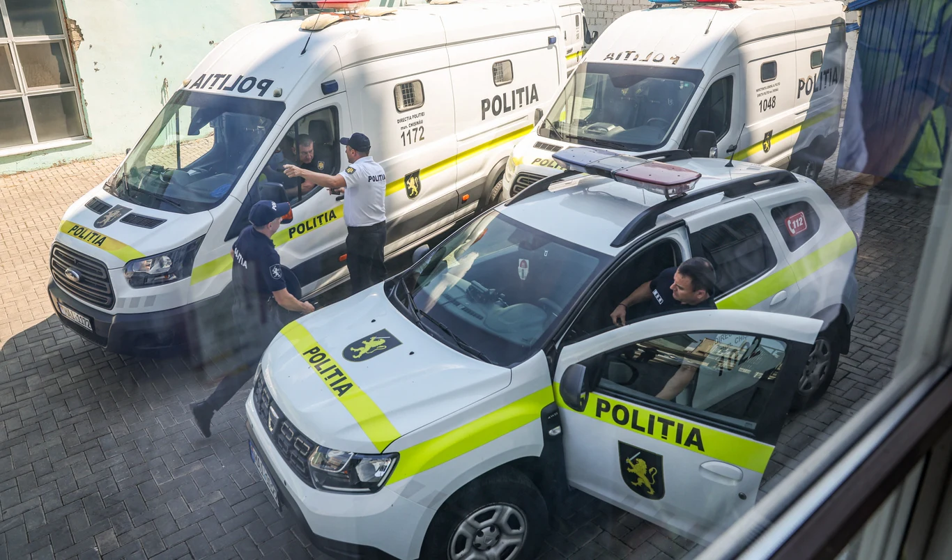 Mołdawska policja przeprowadziła setki przeszukań, uzasadniając akcję działaniami Rosji Trzy policyjne pojazdy z wyraźnym oznaczeniem POLITIA, dwie białe furgonetki i jeden samochód SUV zaparkowane obok siebie na brukowanym placu, kilku umundurowanych policjantów rozmawia lub wsiada do pojazdów.