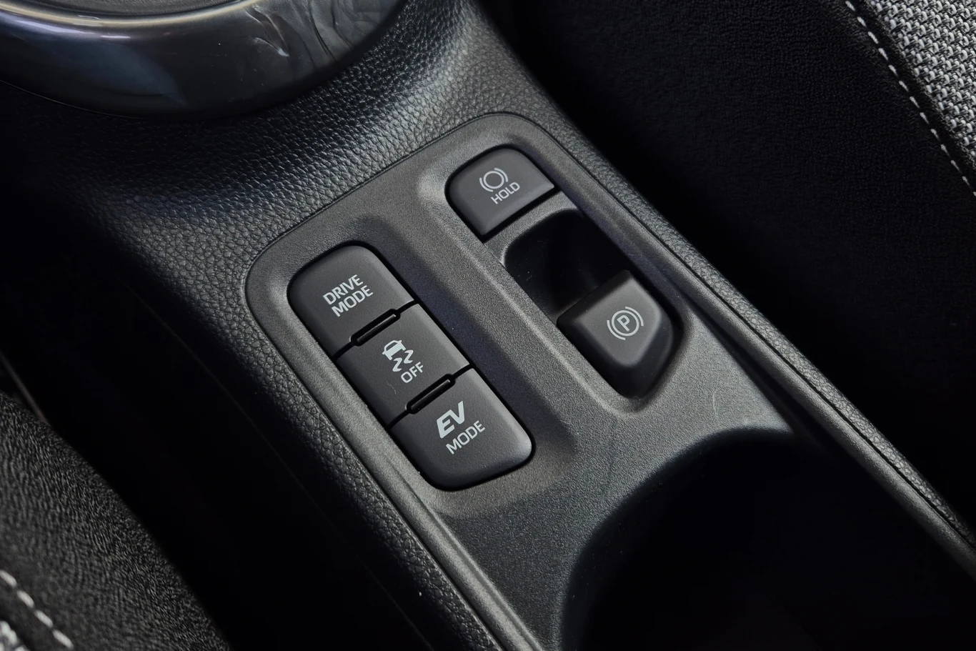 Panel sterowania samochodu z przyciskami do zmiany trybu jazdy, kontroli trakcji, trybu elektrycznego, funkcji autohold oraz elektronicznego hamulca ręcznego