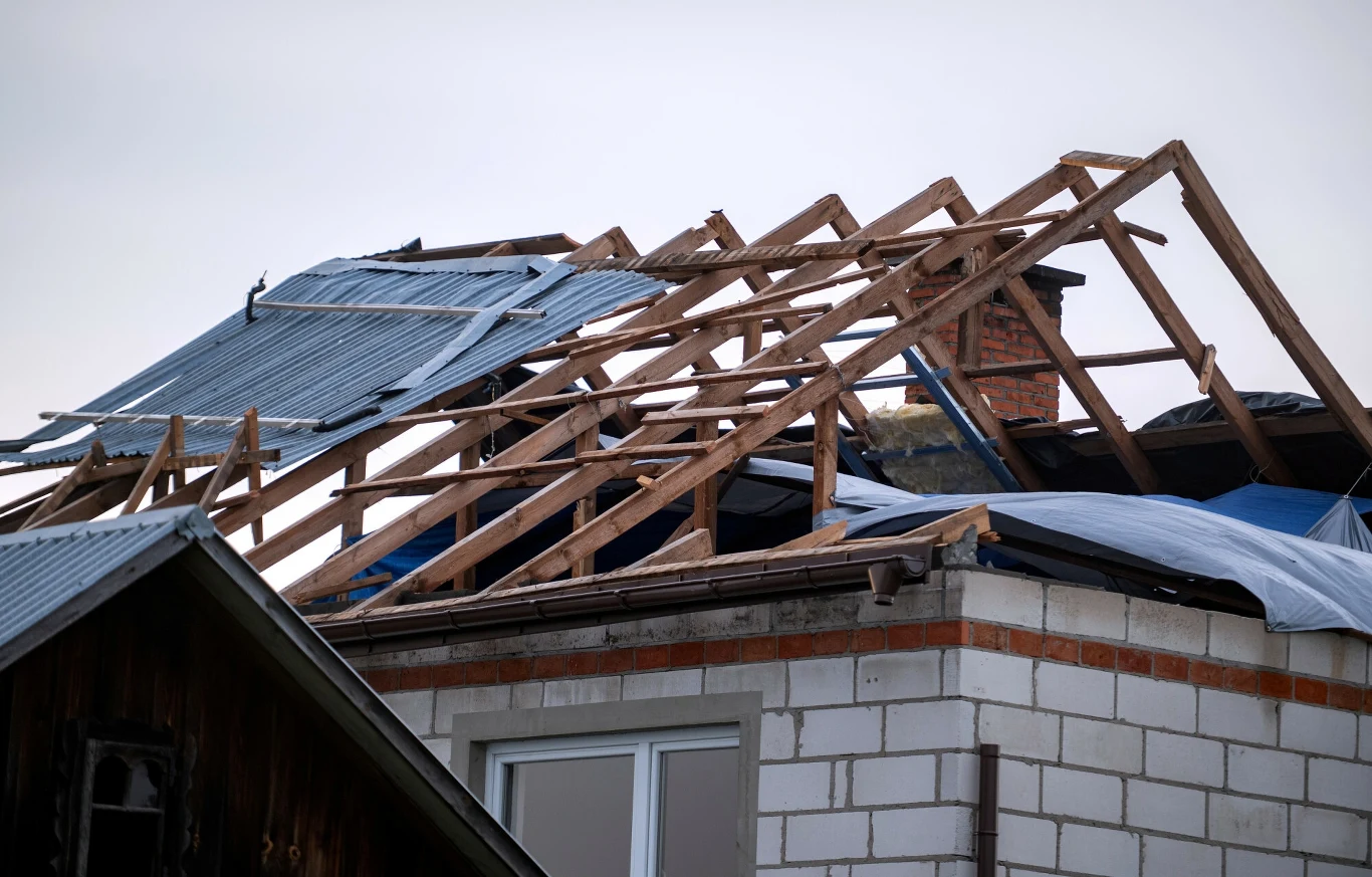 Niejasne są zapisy ubezpieczeń w kontekście zniszczeń spowodowanych dronami Zniszczony dach budynku z widoczną drewnianą konstrukcją, niektóre elementy blachy leżą na połaciach, część dachu została oderwana, a fragment budynku wykonany jest z cegły i bloczków.