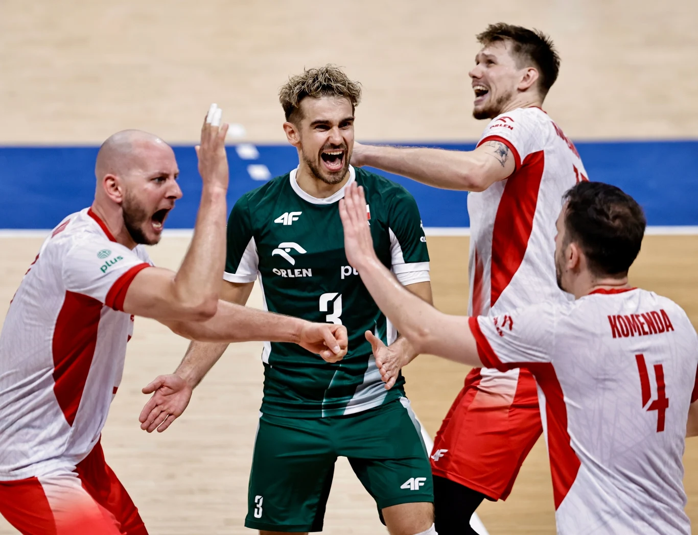 Siatkarze reprezentacji Polski Czterech siatkarzy ubranych w biało-czerwone i zielone stroje celebruje zdobycie punktu na boisku, w tle widoczna drewniana podłoga hali sportowej.