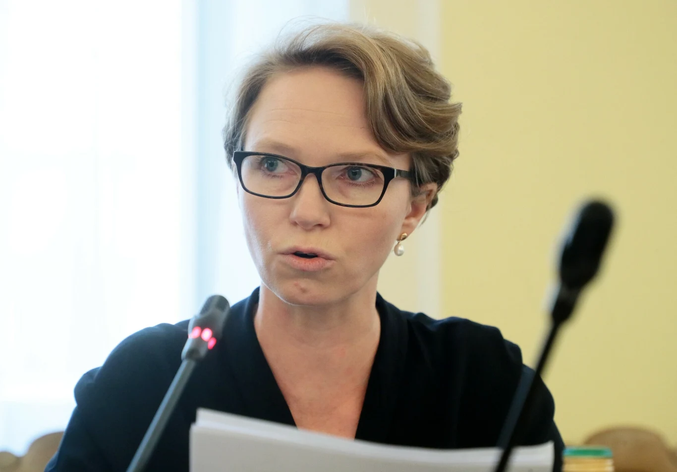 Pierwsza wiceprezes NBP Marta Kightley uważa, że wejście w życie systemu ETS2 będzie poważnym zagrożeniem dla kształtowania się inflacji w Polsce Kobieta w okularach siedzi przy stole konferencyjnym, trzyma dokumenty w dłoniach oraz mówi do mikrofonu, w tle rozmyte elementy sali.