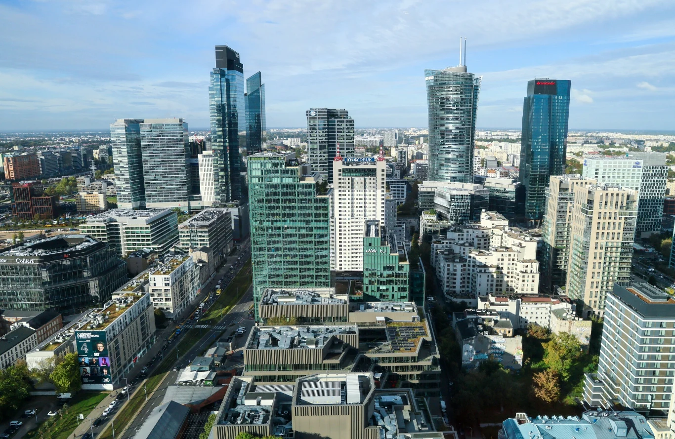 Sprzedano najdroższy pod względem ceny za metr kwadratowy apartament w Polsce (zdj. ilustracyjne) Panorama nowoczesnego centrum miasta z licznymi drapaczami chmur, wysokimi budynkami biurowymi oraz gęstą zabudową miejską w otoczeniu dróg i terenów zieleni.