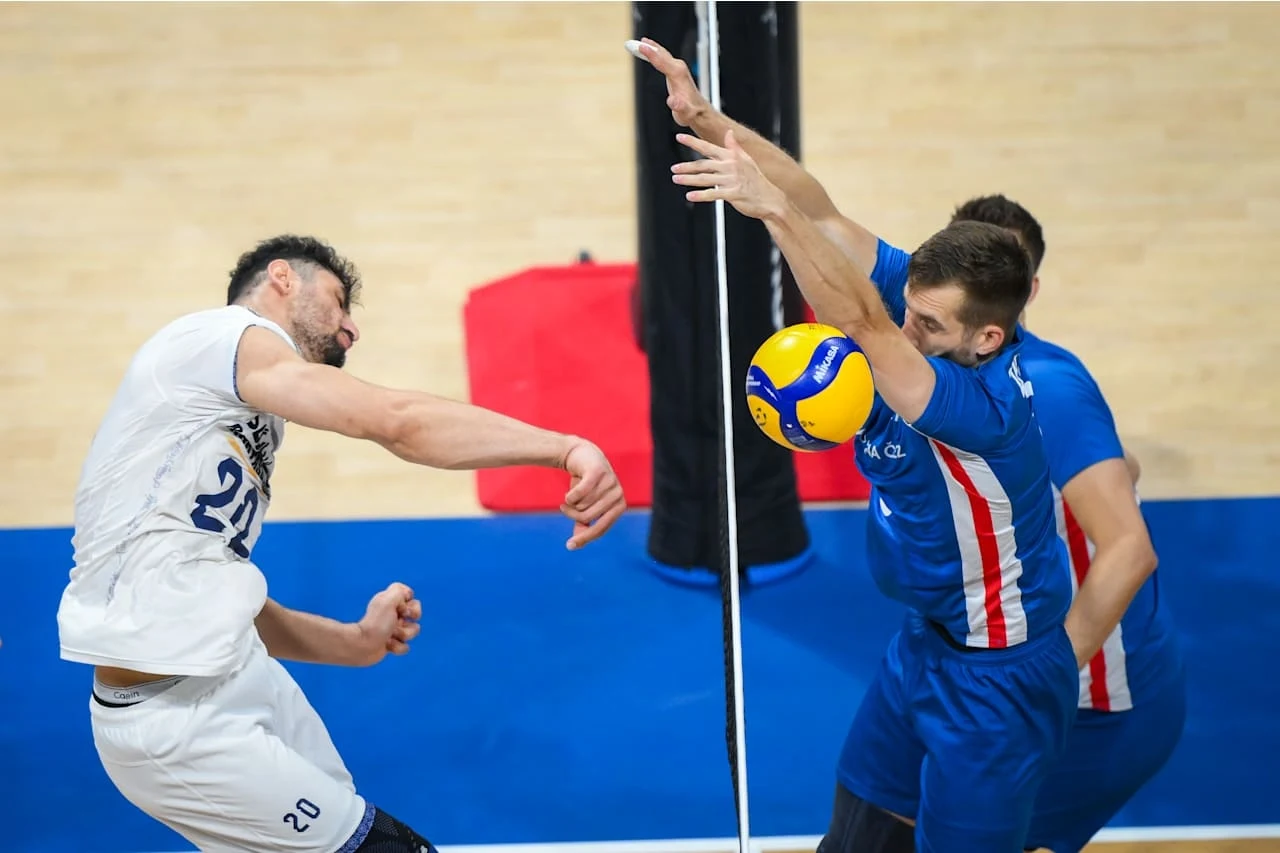 MŚ siatkarzy. Kadr z ćwierćfinału Czechy - Iran Dwóch siatkarzy rywalizuje przy siatce, jeden z nich blokuje piłkę, podczas gdy drugi wykonuje atak; scena dynamiczna, podkreślająca sportową walkę i wysiłek zawodników.