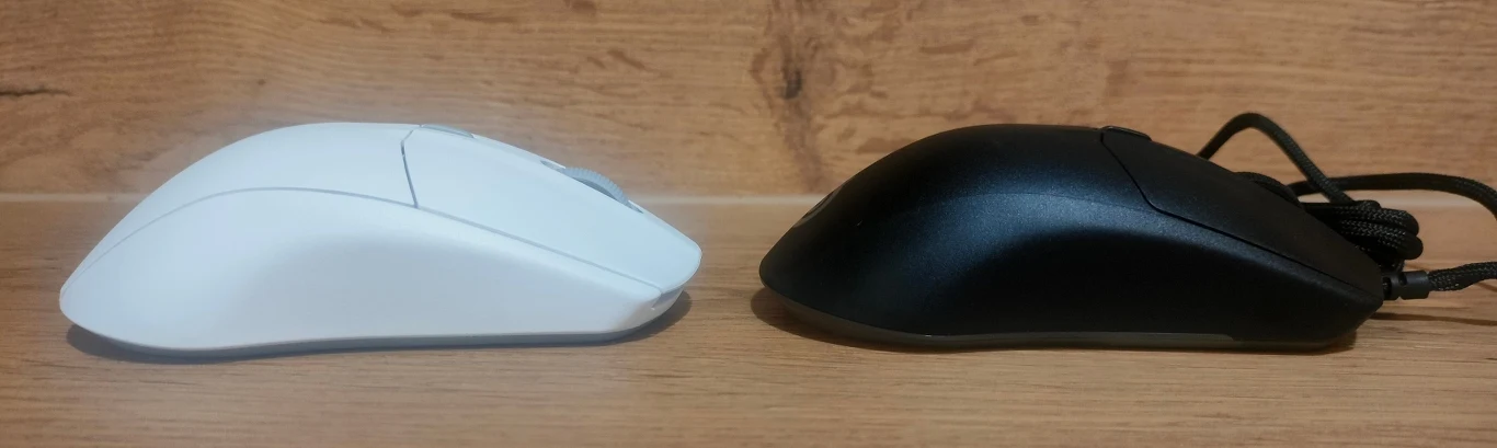SteelSeries Rival 3 Gen 2 i Rival 3 Gen 2 Wireless Dwie myszki komputerowe w kolorach białym i czarnym ustawione obok siebie na tle drewnianej powierzchni.