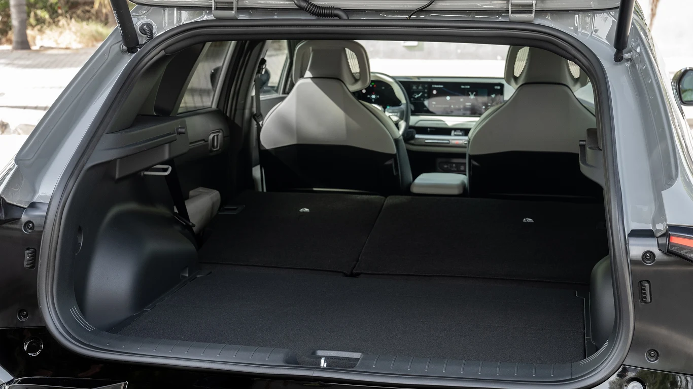 Bagażnik mieści 435 litrów, ale wygląda na mniejszy. Wnętrze bagażnika samochodu z rozłożonymi tylnymi siedzeniami, widok na przestronną przestrzeń ładunkową, przód pojazdu z kierownicą i deską rozdzielczą oraz dwa fotele przednie.