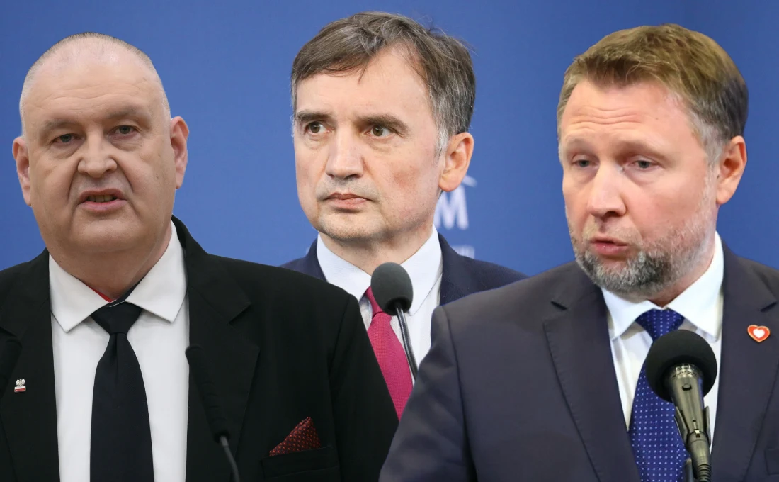 Spięcie na linii MSWiA - Trybunał Konstytucyjny. W tle sprawa Zbigniewa Ziobry Trzech mężczyzn w garniturach stoi na tle niebieskiej ściany z mikrofonami, skupieni na rozmowie lub wystąpieniu publicznym.