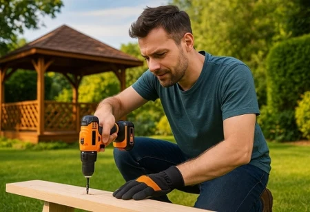 Mężczyzna wierci dziurę w desce wiertarką Niteo