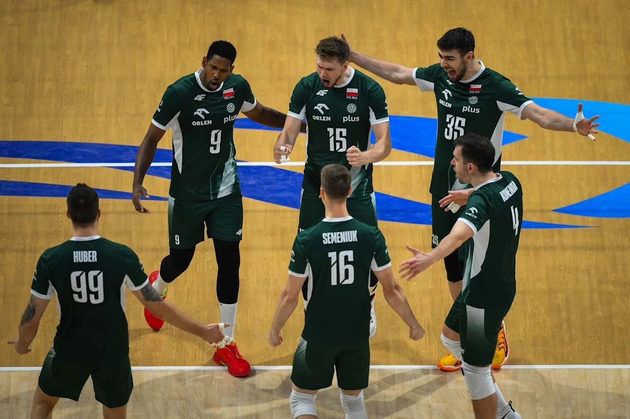 Grupa siatkarzy w zielonych strojach świętuje udaną akcję na hali sportowej, wszyscy zawodnicy skierowani są ku sobie i unoszą ręce w geście radości, wyrażając energię i drużynową jedność.