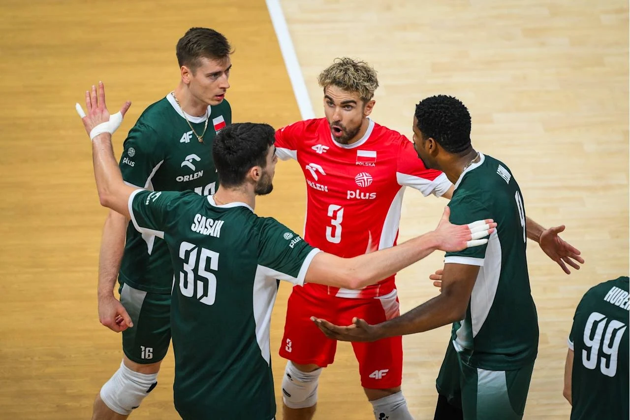 Reprezentacja Polski Czterech siatkarzy w sportowych strojach dyskutuje na boisku, jedna osoba w czerwonym stroju, pozostali w zielonych, intensywna wymiana zdań po zakończonej akcji, emocje widoczne w gestykulacji zawodników.