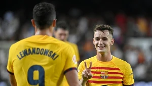 Dwóch piłkarzy FC Barcelony w żółtych koszulkach drużyny na boisku, jeden z nich pokazuje znak pokoju dłońmi, obaj wyglądają na zadowolonych po zakończonym meczu