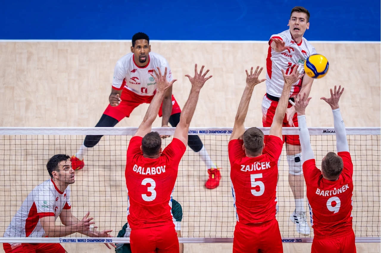 Kadr z meczu Polska - Czech o brązowy medal mistrzostw świata Drużyna siatkarska w białych i czerwonych strojach wykonuje atak przy siatce na tle drużyny w czerwonych koszulkach próbującej zablokować uderzenie, widoczne skupienie zawodników i dynamika gry podkreślają sportowy charakter sceny.