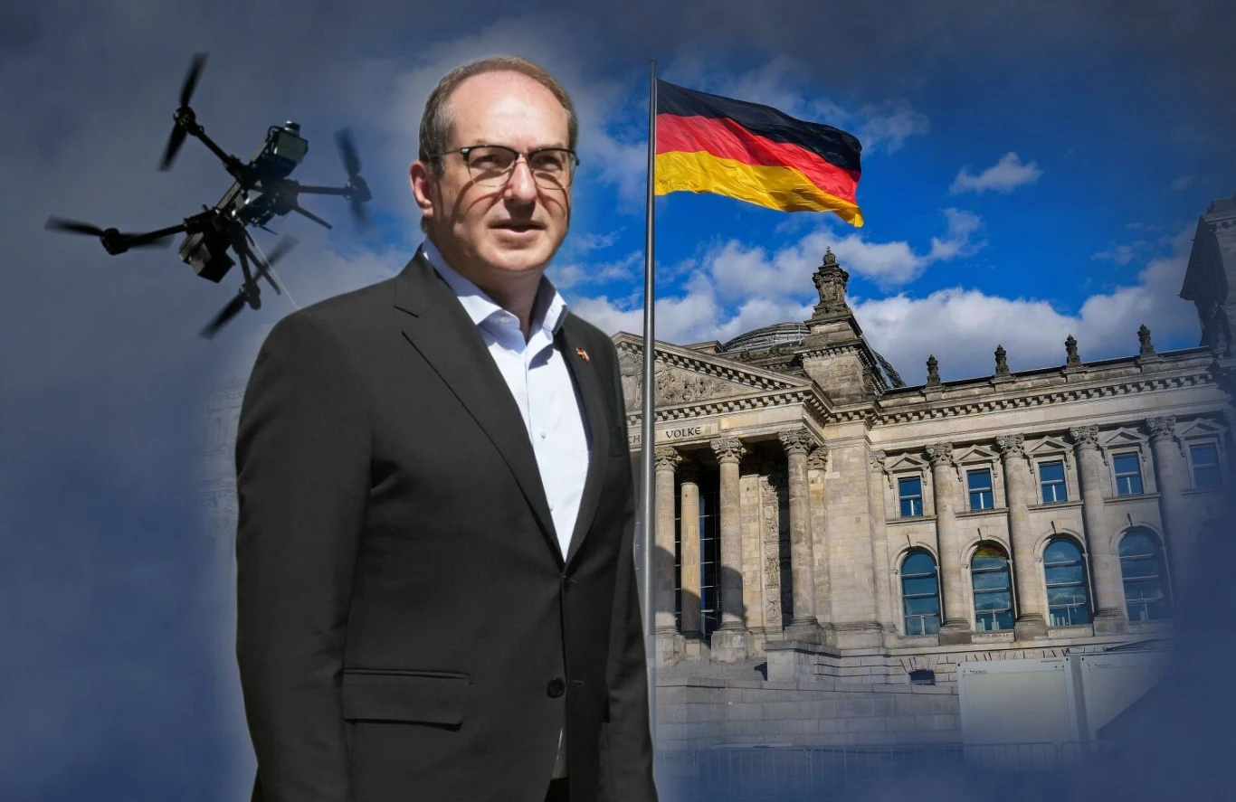 Niemcy chcą zestrzeliwać obcedrony, które pojawią się na terytorium kraju Mężczyzna w garniturze na tle niemieckiego parlamentu, obok którego powiewa flaga Niemiec, w lewym górnym rogu widoczny dron na tle nieba z chmurami.