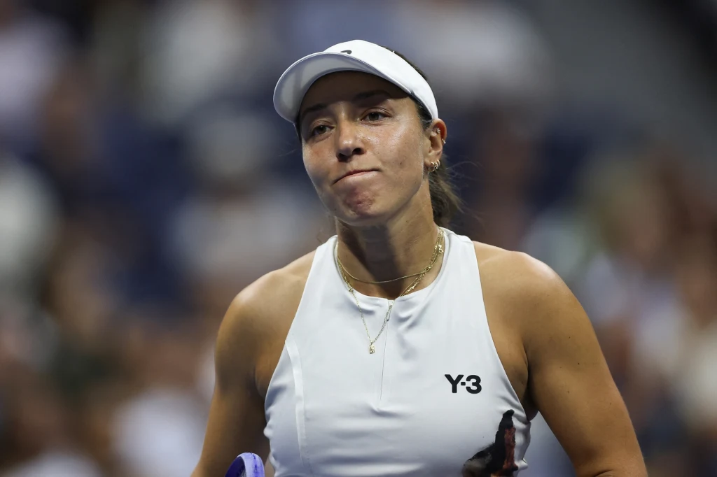 Jessica Pegula Sportsmenka w białej koszulce i czapeczce podczas meczu tenisowego, w tle rozmyte trybuny stadionu.