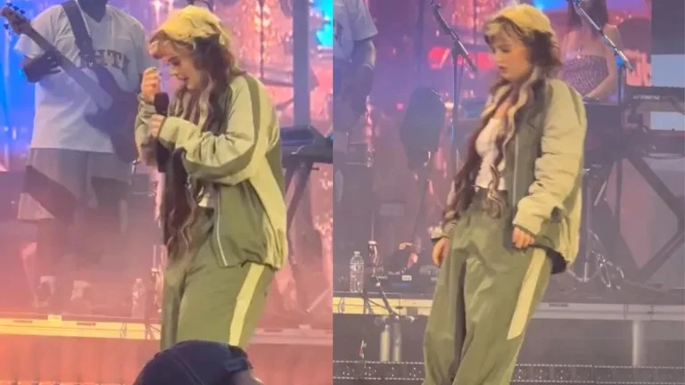 Młoda kobieta w luźnym stroju sportowym i czapce stoi na scenie i śpiewa do mikrofonu, w tle instrumenty muzyczne i członkowie zespołu tworzą koncertowy klimat.