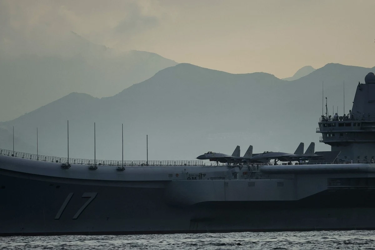 Chiny mają przyjąć militarne wsparcie Rosji (zdj. ilustracyjne) Okręt wojenny z widocznymi myśliwcami na pokładzie na tle górzystego krajobrazu i spokojnej tafli wody.