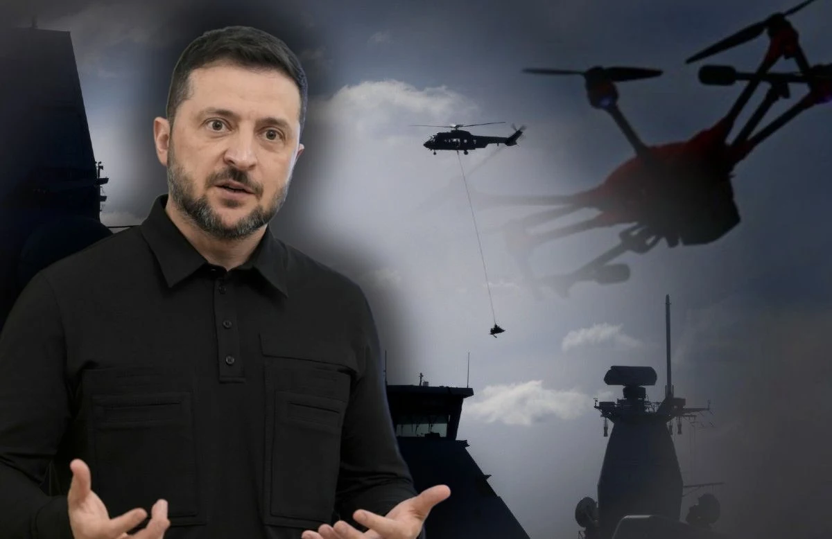 Wołodymyr Zełenski mówi, że Rosja wysyła swoje drony nad Europę z tankowców Mężczyzna w czarnej koszuli gestykuluje przed tłem z sylwetkami pojazdów wojskowych, śmigłowca i drona unoszących się na niebie.