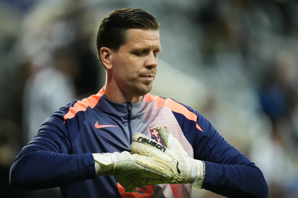 Wojciech Szczęsny Bramkarz w sportowym stroju podczas przygotowań do meczu, ujęcie skupione na koncentracji i skupieniu zawodnika, widoczne rękawice bramkarskie oraz logotyp sportowy na ubraniu.