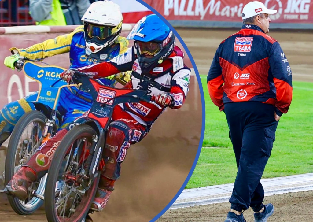 Polonia Bydgoszcz przegrała baraż o Ekstraligę. Klub zwolnił trenera Tomasza Bajerskiego. Dwóch motocyklistów w kolorowych kombinezonach ściga się na torze żużlowym, obok widoczny członek zespołu ubrany w kurtkę z emblematami sponsorów spaceruje po zielonej murawie przy torze.