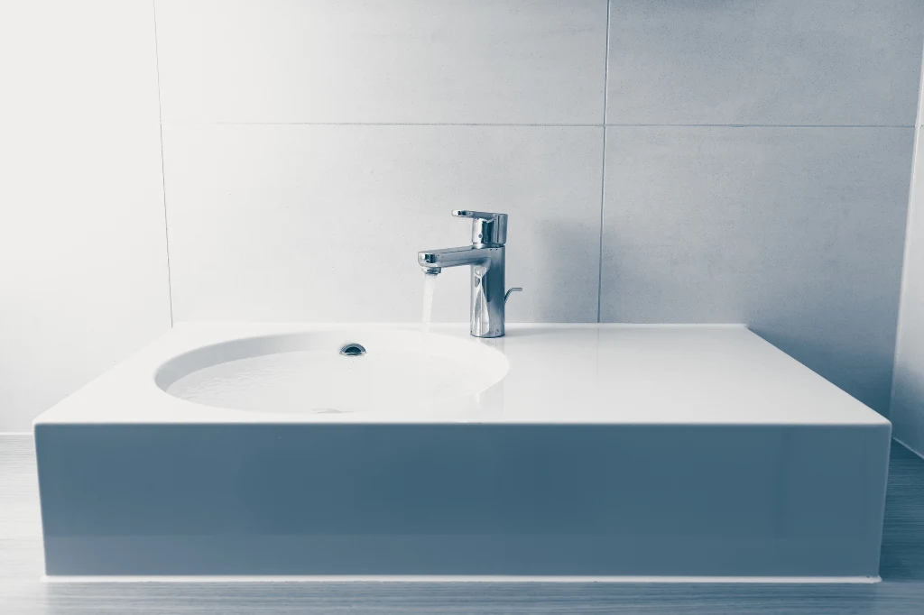 Minimalistyczna, nowoczesna umywalka z chromowaną baterią na tle jasnych płytek ściennych