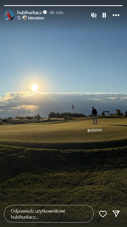 Grający w golfa mężczyzna na zielonym polu golfowym o zachodzie słońca, jasne światło słoneczne na horyzoncie i spokojna atmosfera przy pustej przestrzeni oraz odległych drzewach.