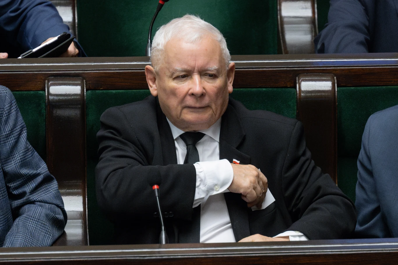 Dolny Śląsk. Jarosław Kaczyński wykluczył siedmiu radnych z klubu PiS Starszy mężczyzna w garniturze siedzi w ławie sejmowej, wkłada rękę do kieszeni marynarki, w tle widoczne inne osoby.