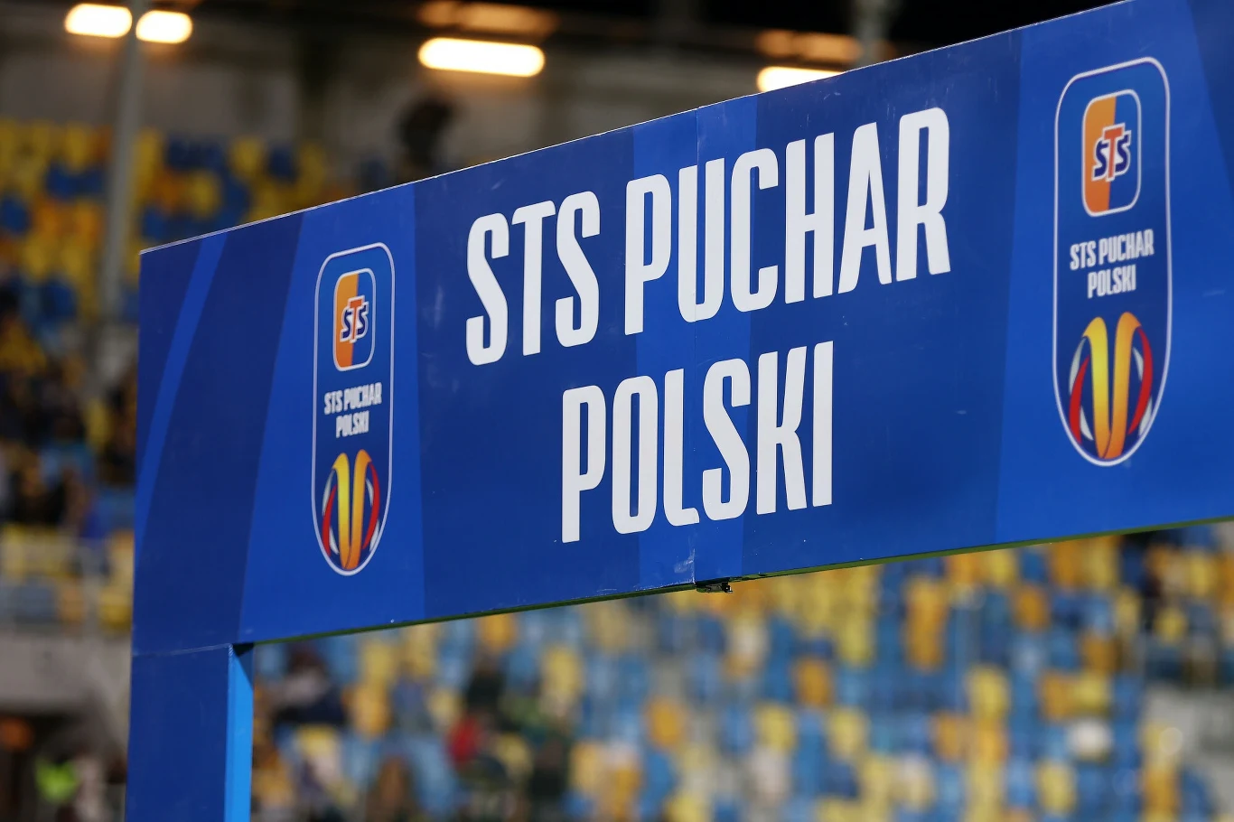 Brama wejściowa oznaczona napisem STS Puchar Polski, na tle stadionu w kolorach niebiesko-żółtych, wykorzystana podczas wydarzenia piłkarskiego.