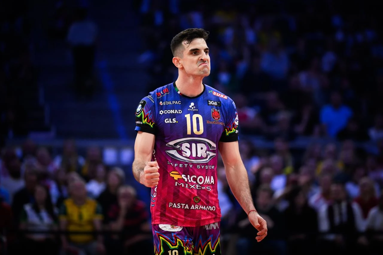 Siatkarz w kolorowym stroju sportowym z numerem 10 na tle rozmytego tłumu kibiców, pokazujący emocje podczas meczu.