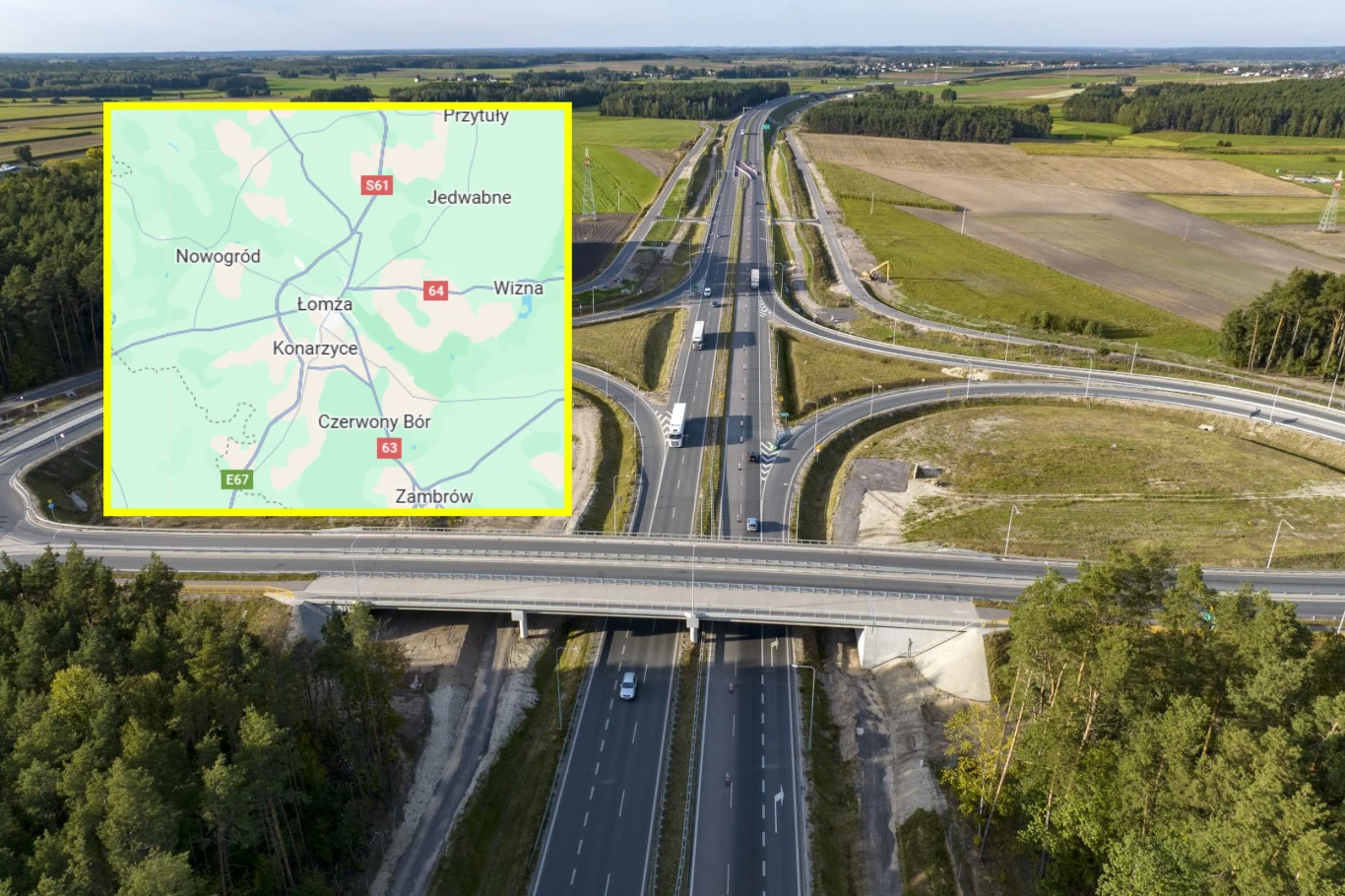 Od dziś kierowcy przejadą obwodnicą Łomży w ciągu drogi ekspresowej S61. / Fot. - Google Maps Nowoczesny węzeł drogowy z kilkoma pasami ruchu otoczony przez pola i lasy, nałożona mapa z zaznaczonymi miejscowościami regionu Łomża podkreśla lokalizację infrastruktury.