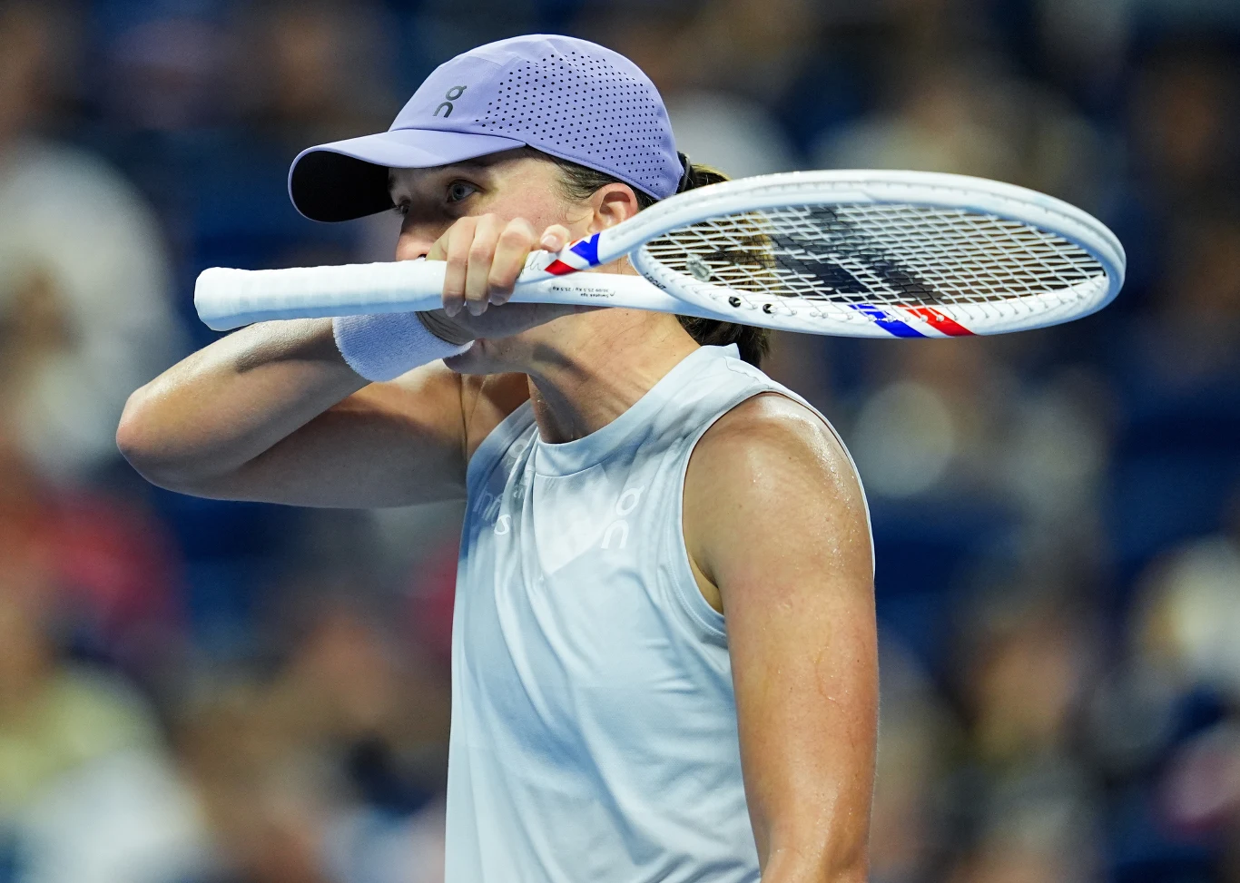 Iga Świątek podczas meczu z Emmą Navarro w Pekinie Tenisistka w sportowej czapce i koszulce trzyma rakietę tenisową przy twarzy, wyraźnie skoncentrowana, na tle rozmytej publiczności.