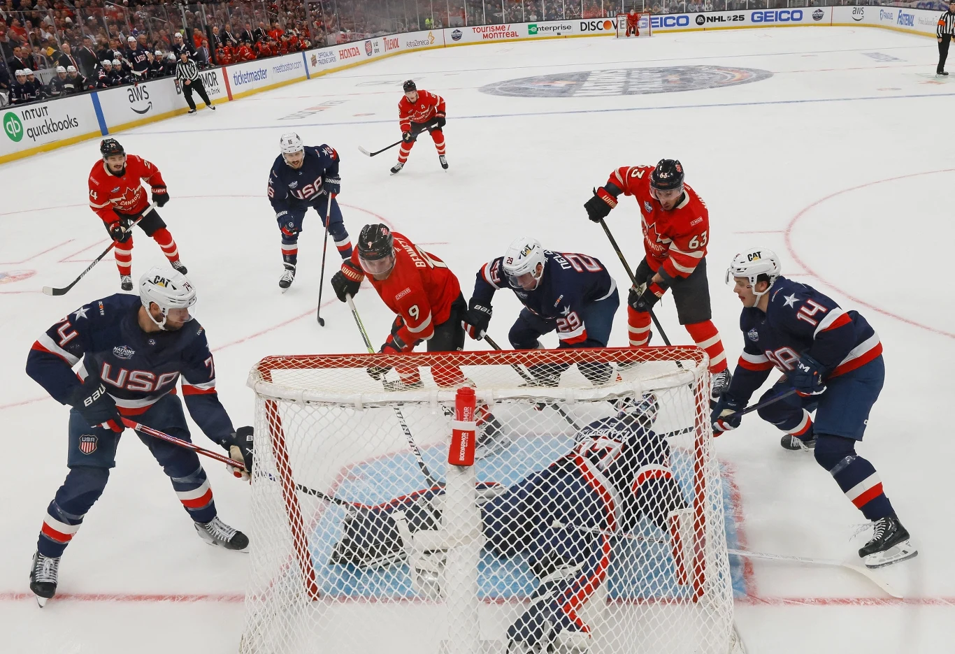 Faworytami do medali w hokeju na zimowych igrzyskach olimpijskich będą m.in. USA i Kanada Intensywna walka o krążek przed bramką podczas meczu hokeja na lodzie, zawodnicy obu drużyn w pełnym skupieniu starają się zdobyć bramkę lub ją obronić, dynamiczna atmosfera na lodowisku, stroje zawodników oznaczone napisami USA oraz czerwonymi koszulk...