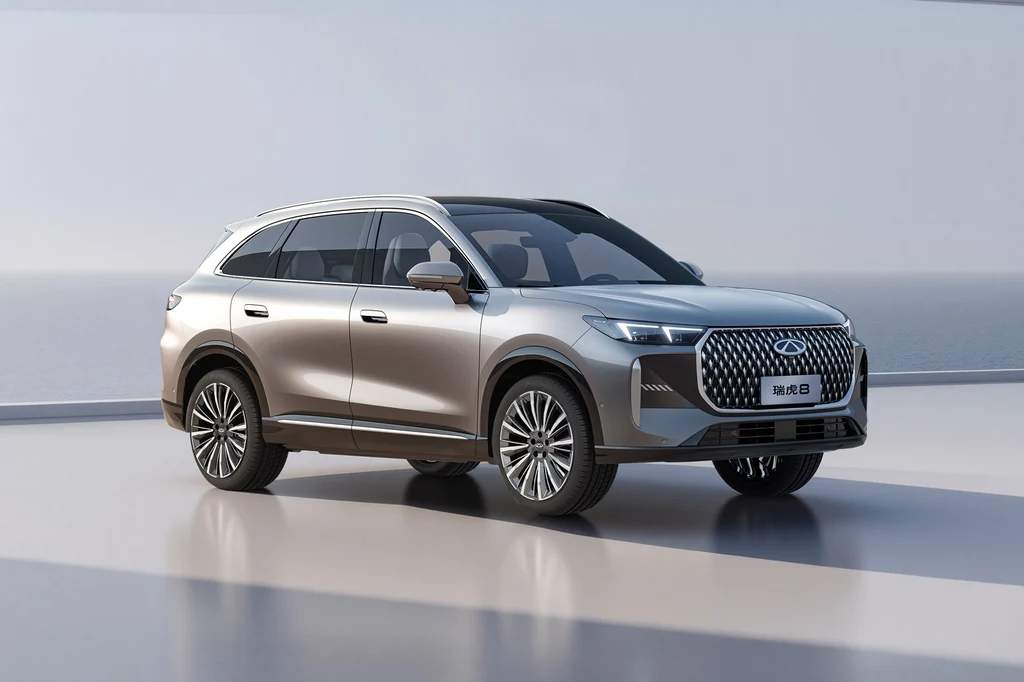 Luksusowy srebrny SUV z przyciemnianymi szybami i nowoczesnym przednim grillem, ustawiony na gładkiej nawierzchni w minimalistycznym, jasnym otoczeniu.