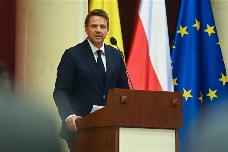 Rafał Trzaskowski ogłosił decyzję ws. nocnej prohibicji w Warszawie Mężczyzna w garniturze przemawia z mównicy, w tle znajdują się flagi Polski, Unii Europejskiej oraz żółta flaga