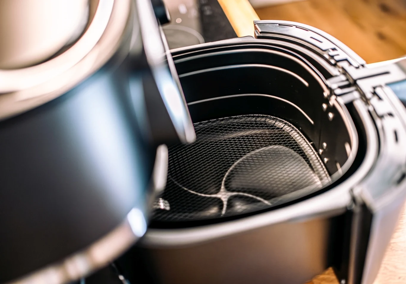 Przeczytałam, że Airfryer marki Philips zużywa 80 proc. mniej energii niż tradycyjny piekarnik klasy A Otwarty kosz frytkownicy beztłuszczowej z widocznym wnętrzem pokrytym siatką, przeznaczonym na przygotowanie potraw beztłuszczowych, ustawiony na blacie kuchennym.